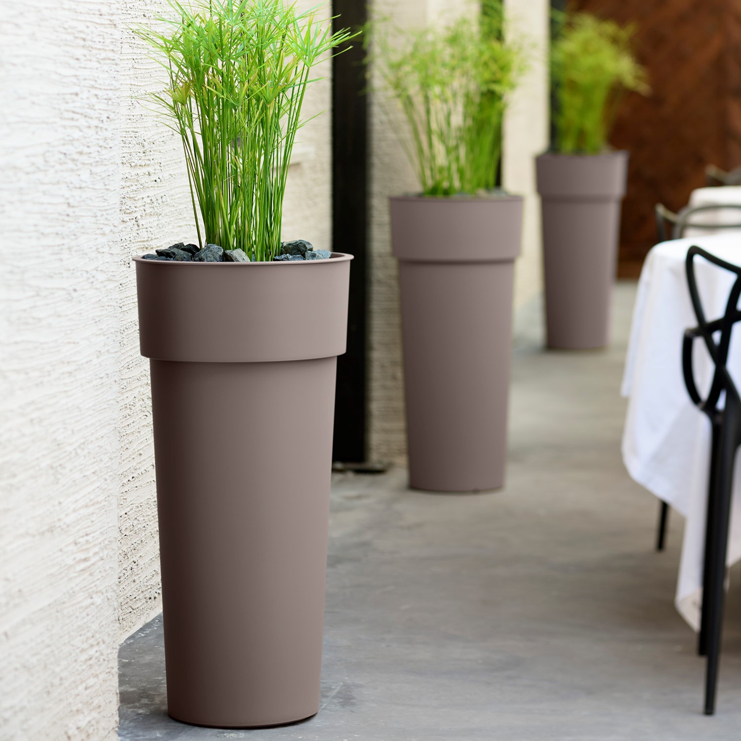 Blumentöpfe DUO in Taupe neben einem Restauranttisch